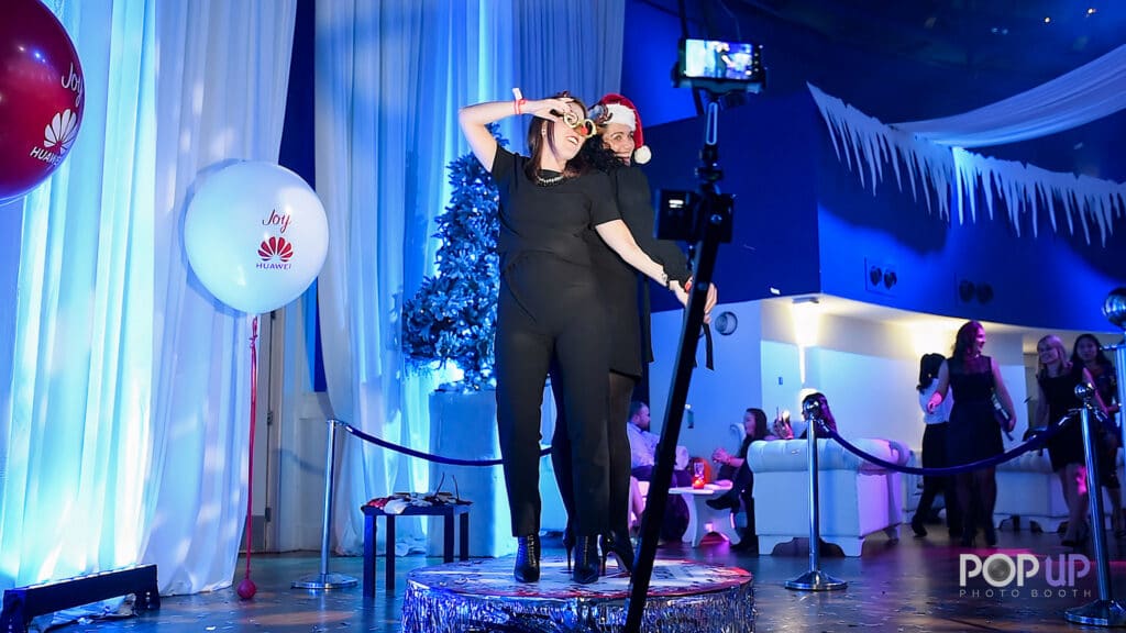 2 women on 360 photo booth at corporate holiday event
